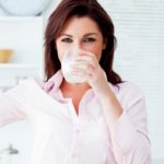 Девушка пьет молоко и показывает бицепс