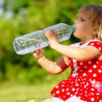 Девочка пьет воду из бутылки