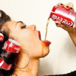 Молодая девушка пьет колу